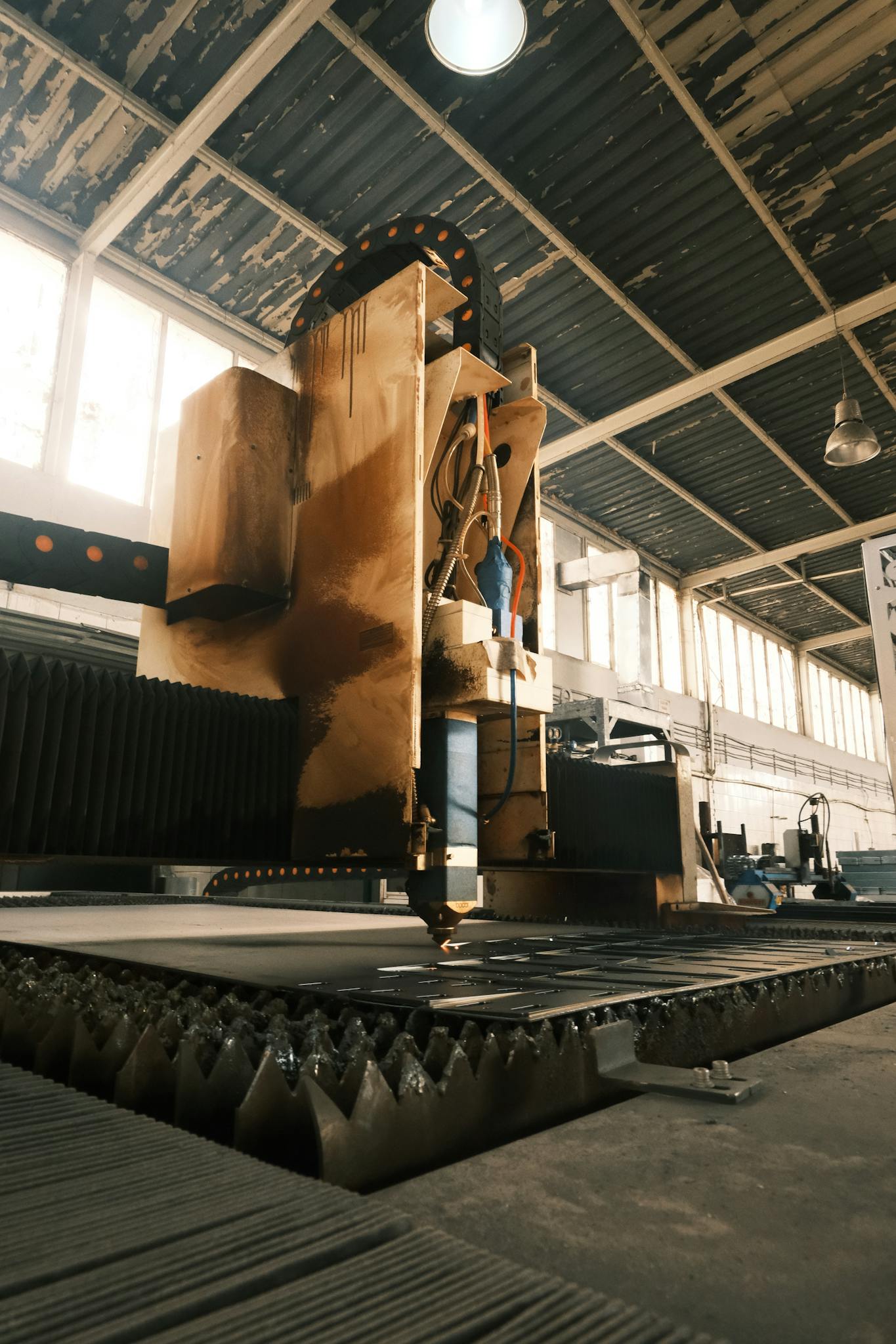 Laser cutting machine working in a sunlit factory environment.